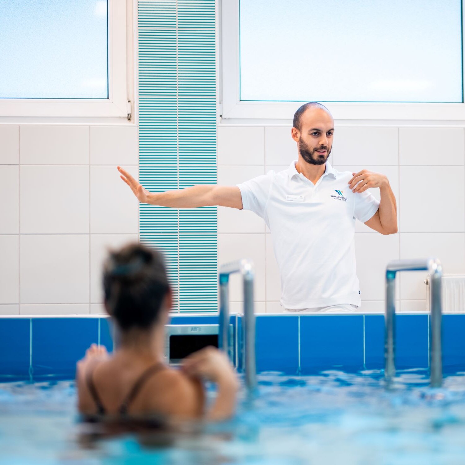 Trainer zeigt Übung bei der Unterwasserheilgymnastik vor